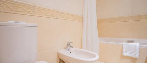 A bathroom with a toilet, bidet, and bathtub.