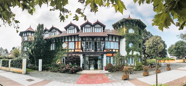 A traditional building with a prominent entrance, a balcony, and a garden area with seating.