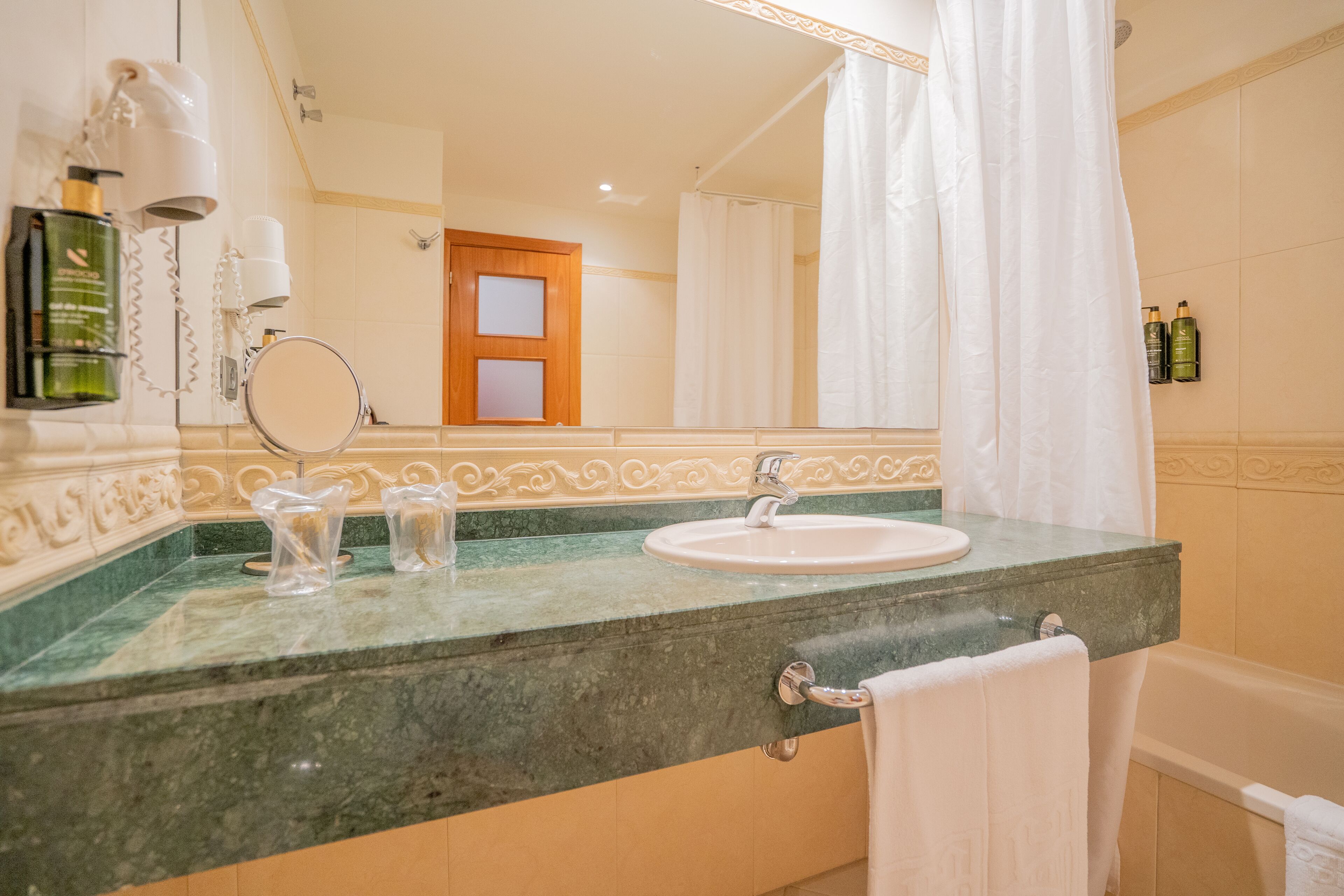 Une salle de bain avec un lavabo, un miroir et un rideau de douche.
