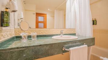 Une salle de bain avec un lavabo, un miroir et un rideau de douche.