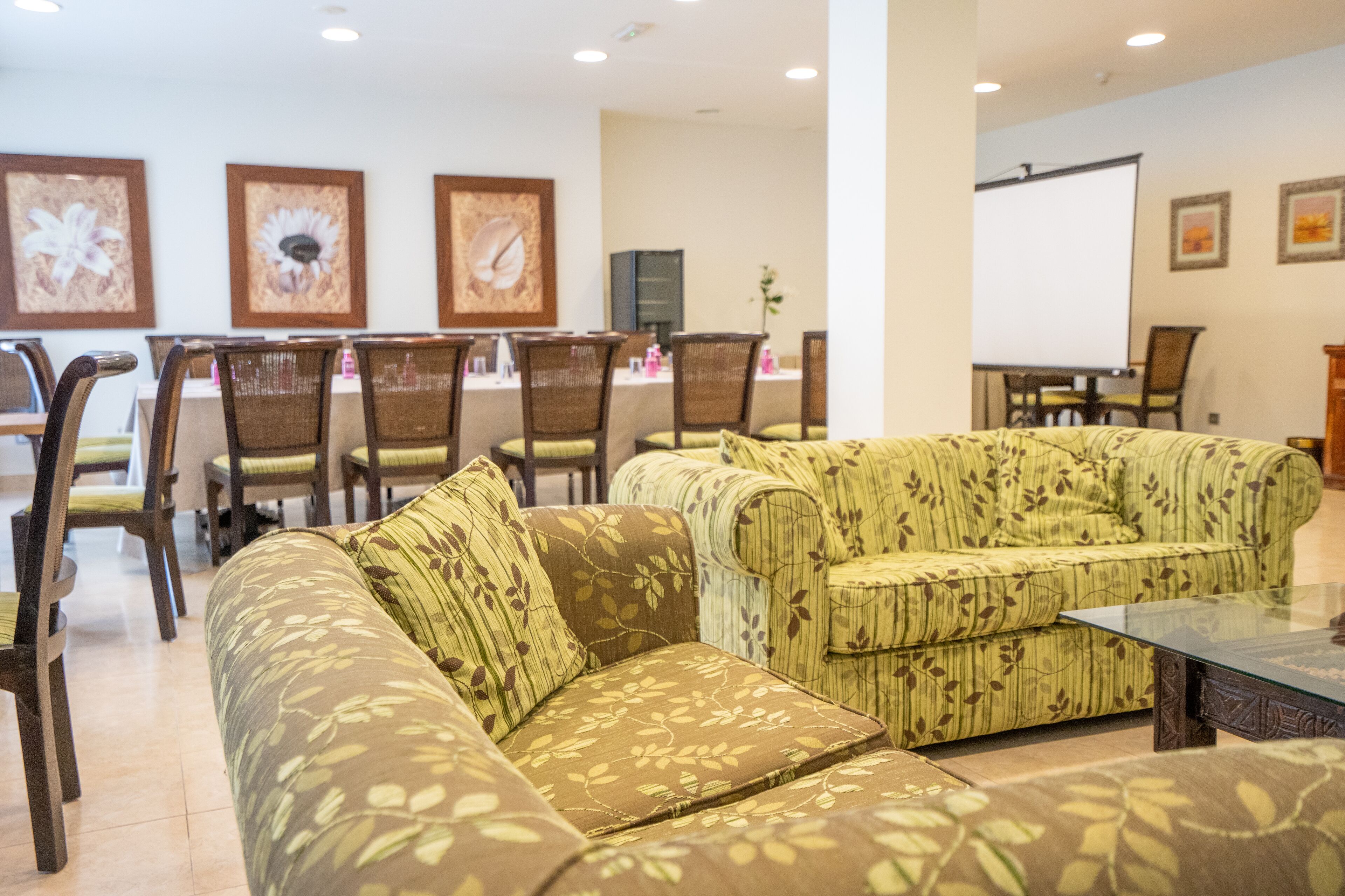 Un vestíbulo de hotel con un sofá, sillas, una mesa de centro y una pizarra en la pared.