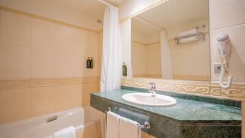 A bathroom with a bathtub, a sink, a mirror, and a hairdryer.