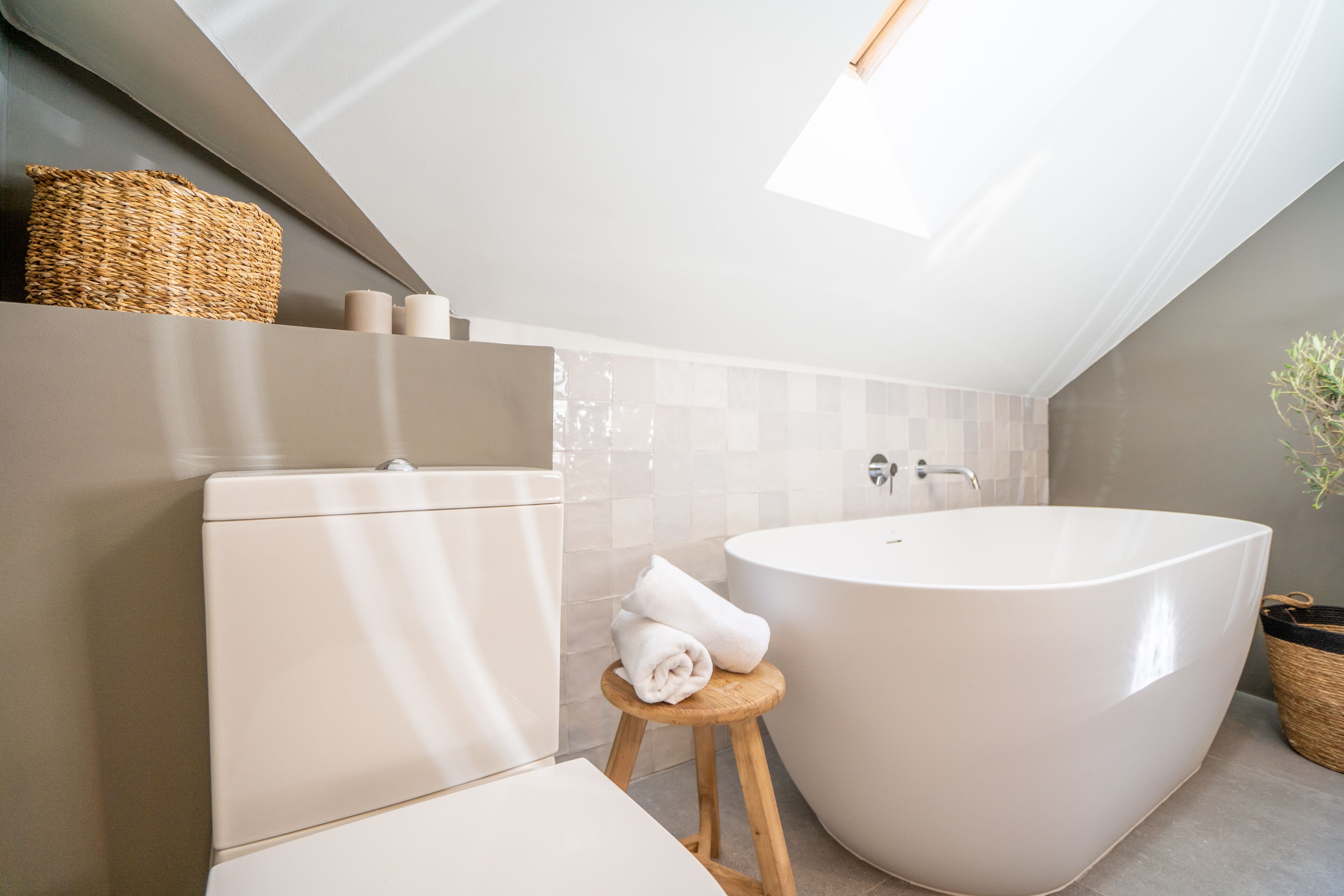 Un bagno moderno con una vasca freestanding, un water e un piccolo sgabello con asciugamani.