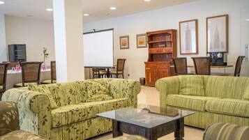 A living room with green-striped sofas, a glass coffee table, a wooden cabinet, and framed pictures on the wall.