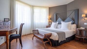 Une chambre d’hôtel avec un grand lit, un bureau, une chaise et une table de chevet avec une lampe.