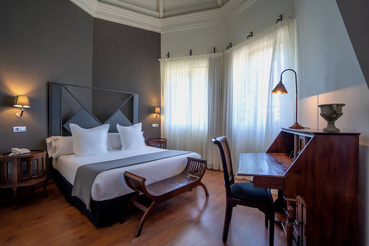 A hotel room with a large bed, bedside tables, a desk, and a chair.