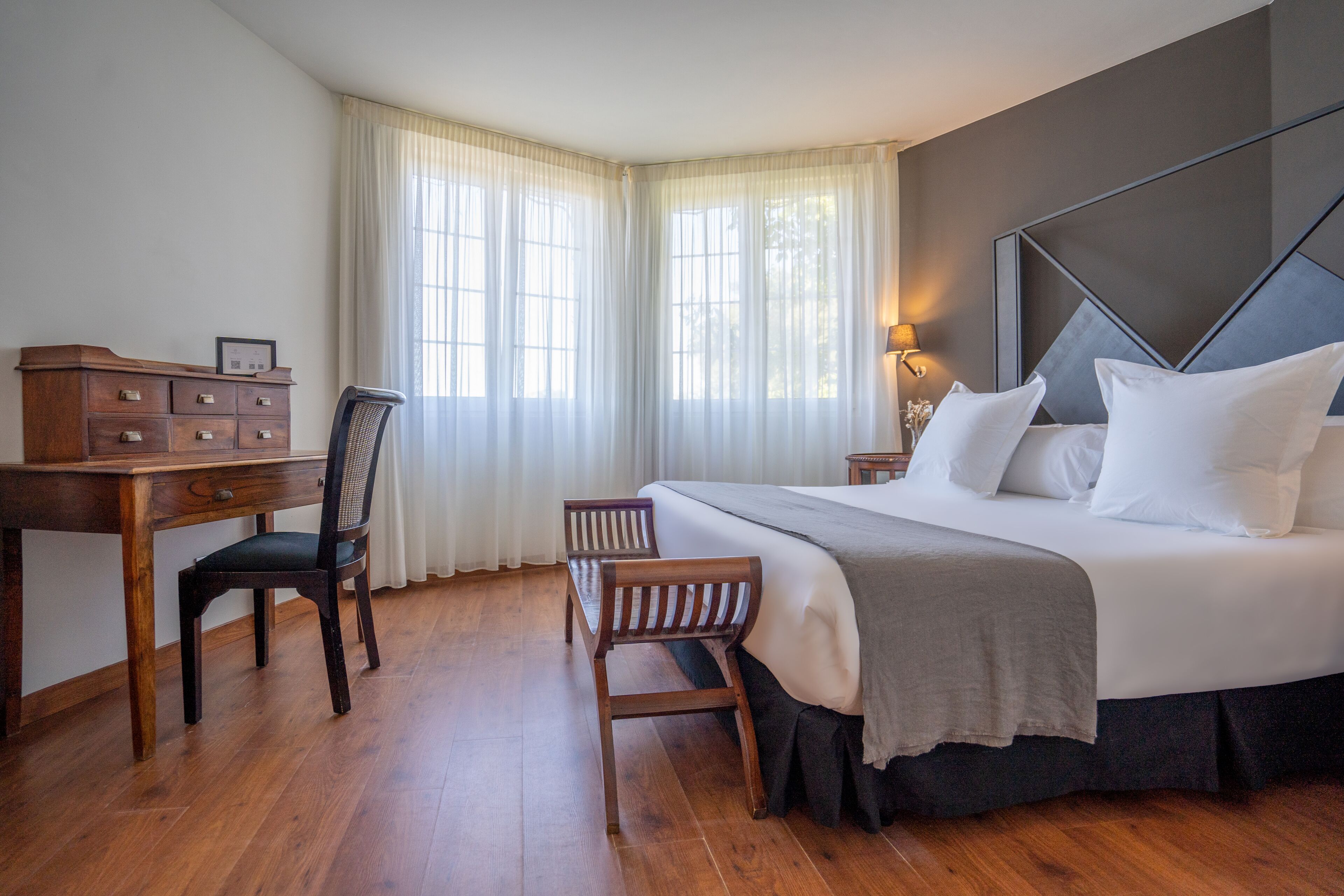 A bedroom with a bed, a desk, a chair, and a dresser.