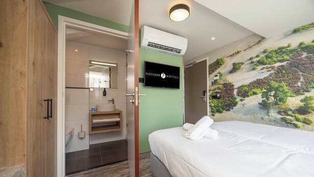 A hotel room with a bed, a bathroom, and a mural on the wall. - Fletcher Hotel Het Witte Huis (Soest)