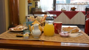 A breakfast table with various food items, a pitcher of orange juice, and a teapot.