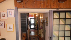A hallway with a wooden ceiling, a patterned rug, and a door with a geometric design.