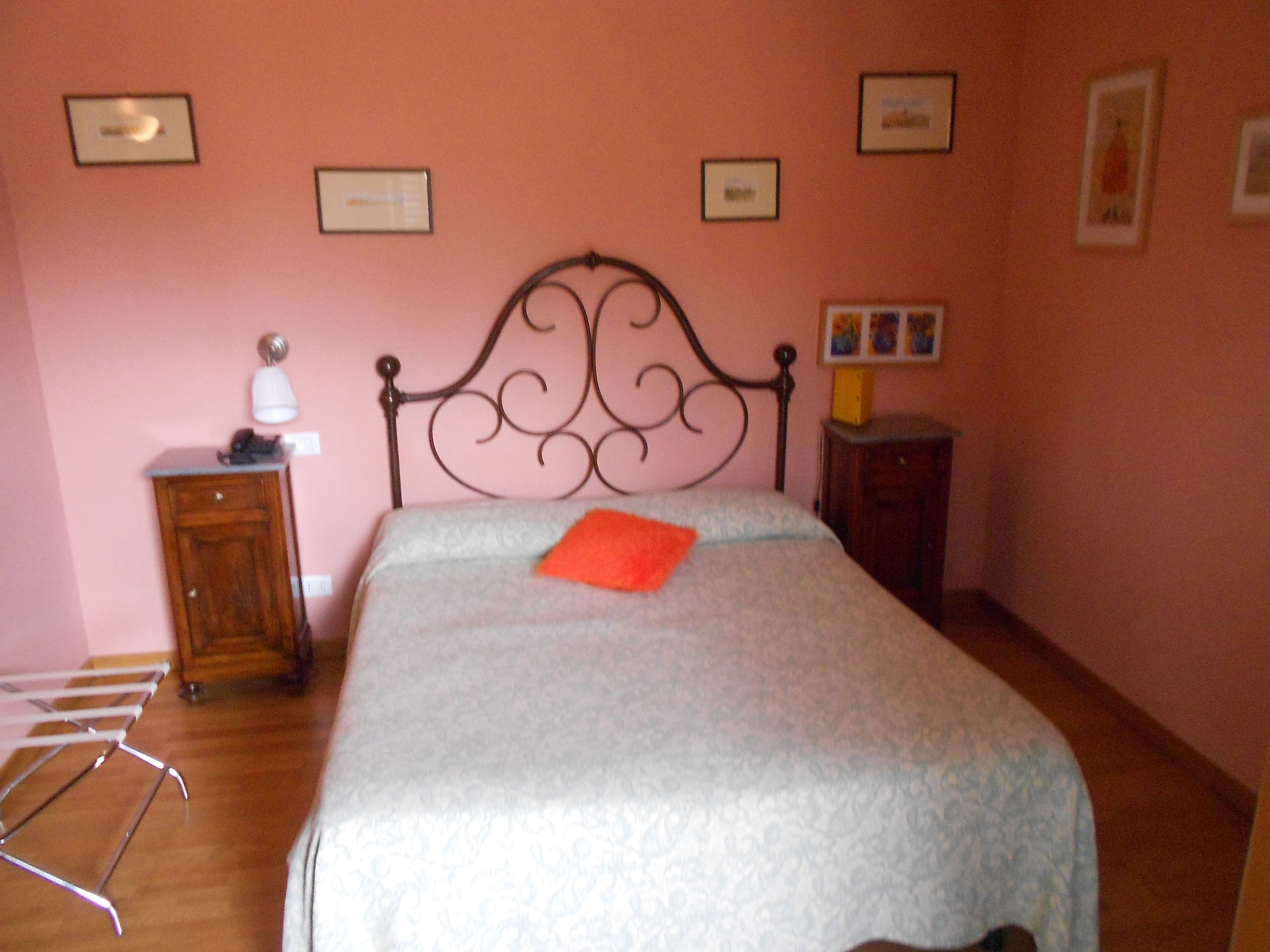A bedroom with a bed, a nightstand, a lamp, and a wardrobe.
