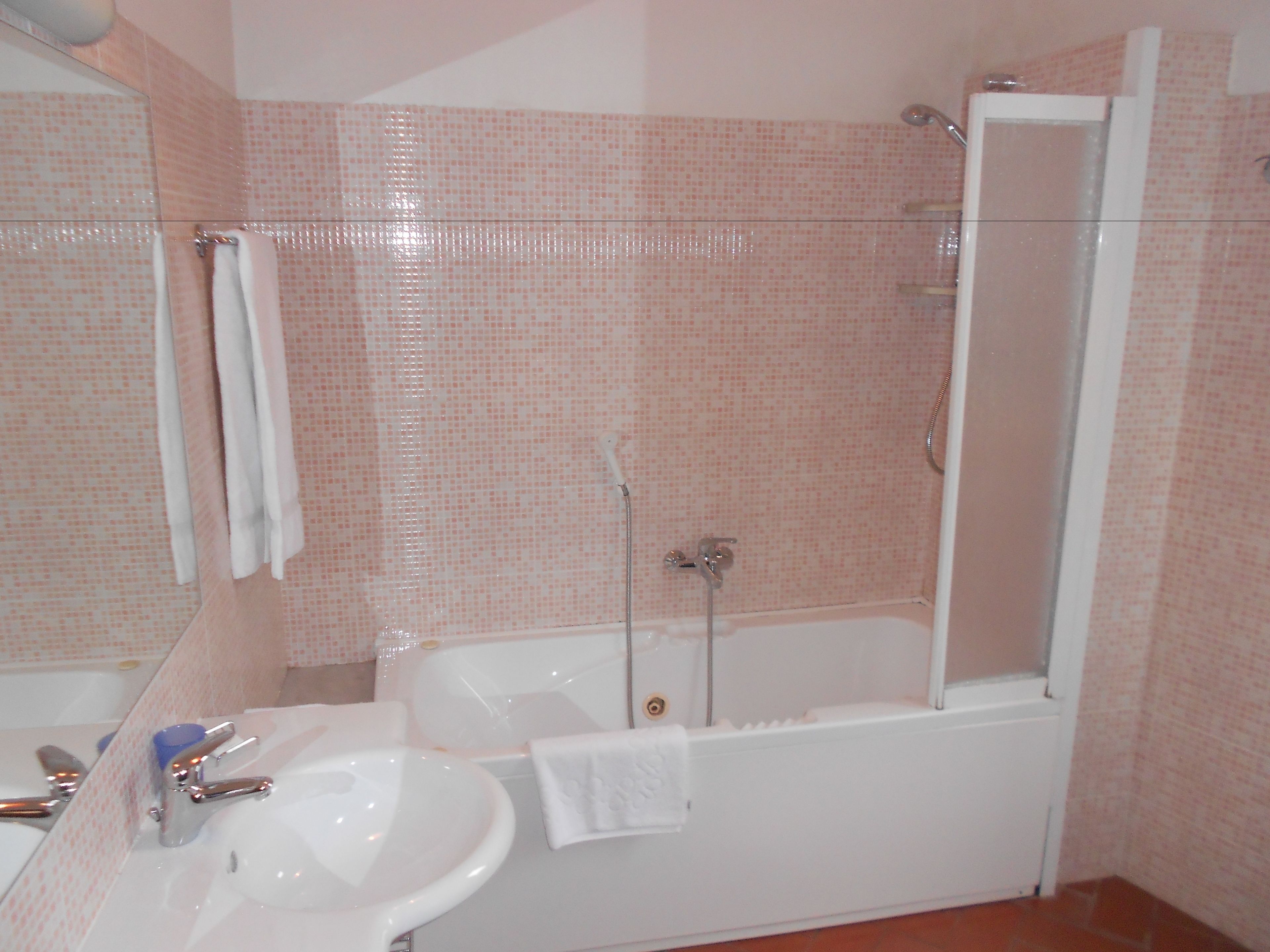 A bathroom with a sink, mirror, and bathtub.