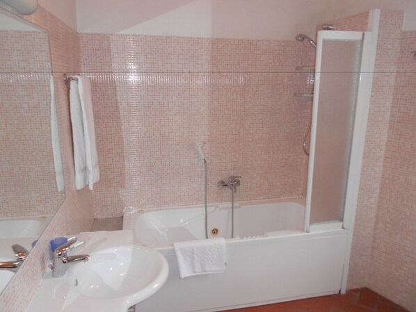 A bathroom with a sink, mirror, and bathtub.