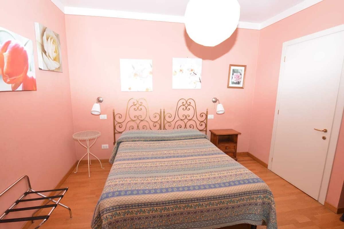 A bedroom with a bed, a chair, a small table, and a door.