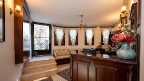 A grand entryway with a wooden staircase, a bench, and a reception desk.