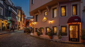 A cobblestone street lined with historic buildings, including a pink building with a sign for a restaurant.