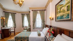 A hotel room with two beds, a desk, a chair, a vanity with a mirror, and a painting on the wall.