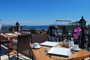 A terrace with dining tables set for two, equipped with white plates, cups, and cutlery. - Osmanhan Hotel (Istanbul)