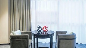 A room with a round table, two armchairs, and a window with curtains. - Rebecca Hotel (Zhengzhou)