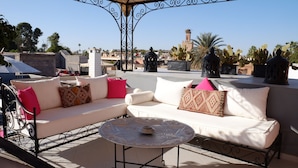 Una terraza en la azotea con un conjunto de sofá blanco, una mesa redonda y cactus decorativos.