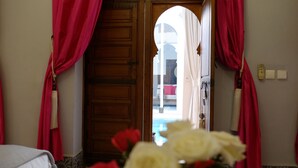 Habitación de hotel con puerta de madera, cortinas rojas y vistas al exterior.