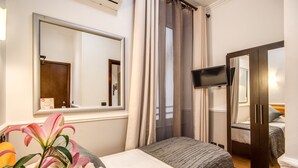 Ein Hotelzimmer mit einem Bett, einem Fernseher, einem Spiegel und einem Fenster mit Vorhängen.