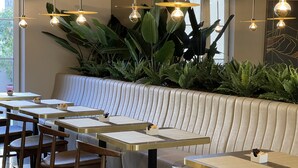 Interior de restaurante con cabinas, mesas y lámparas colgantes.