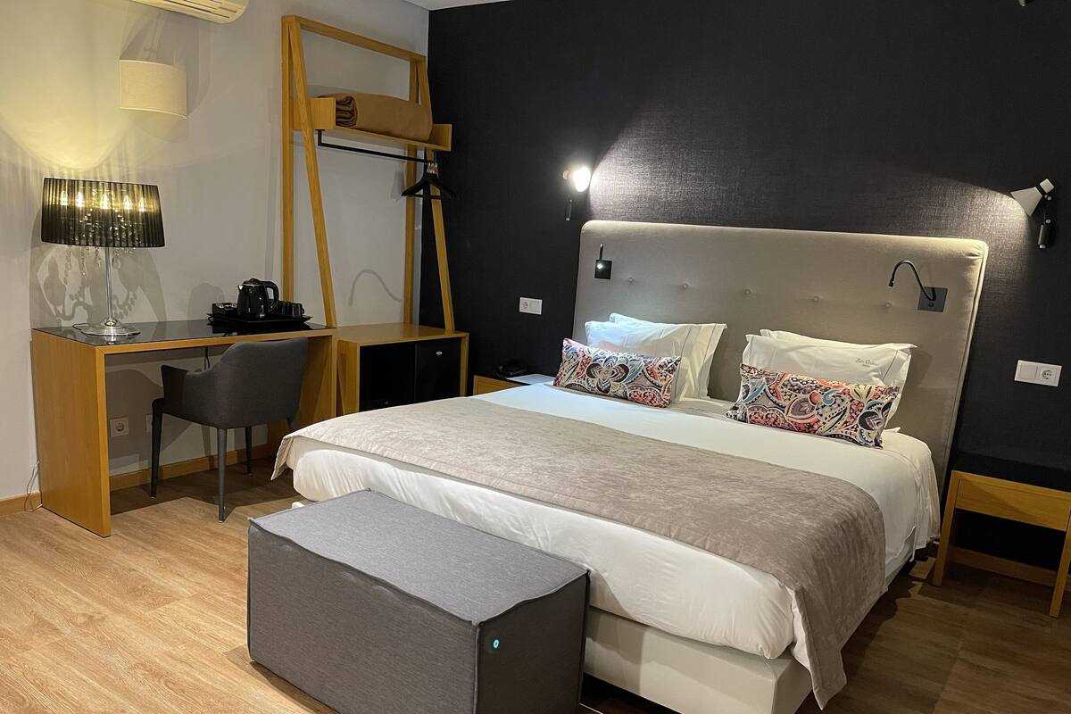 A modern bedroom with a bed, bedside tables, a desk, and a chair.