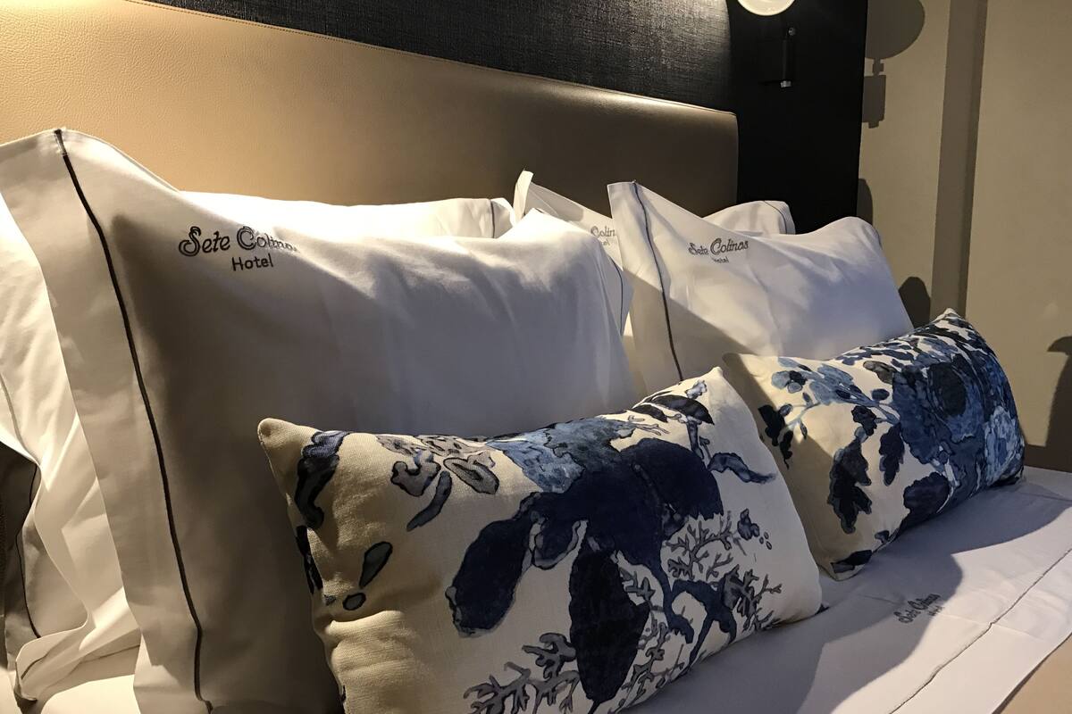 A bed with two pillows, one plain and one with a floral pattern, and a headboard.