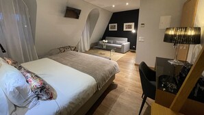 Un dormitorio moderno con una cama, un escritorio, una silla, un sofá y una mesita.