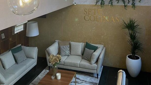 Un interior moderno con lámparas colgantes de cristal, un conjunto de sofá, una mesa de centro y una estantería para plantas en la pared.