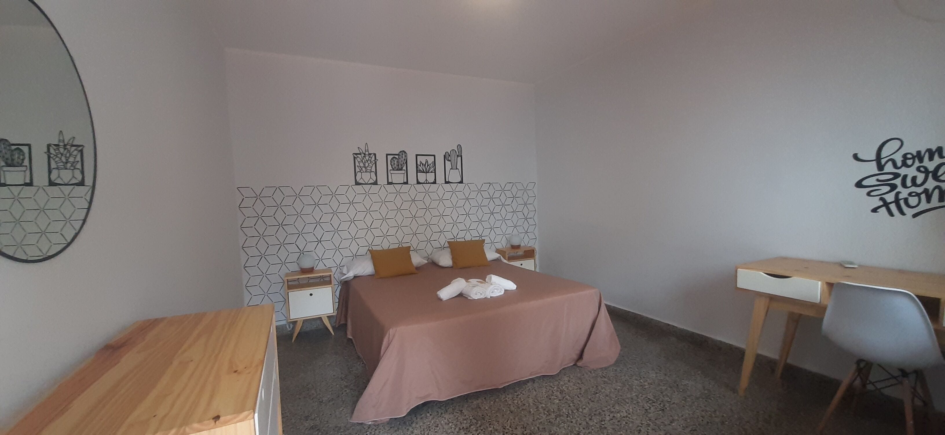 A bedroom with a bed, bedside tables, a desk, and a chair.