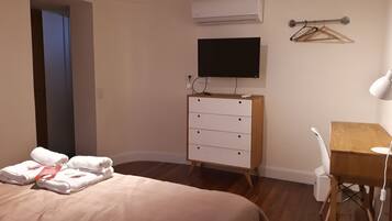 Une chambre d’hôtel équipée d’un lit, d’un bureau, d’une chaise, d’une commode, d’un appareil de climatisation et d’un téléviseur.