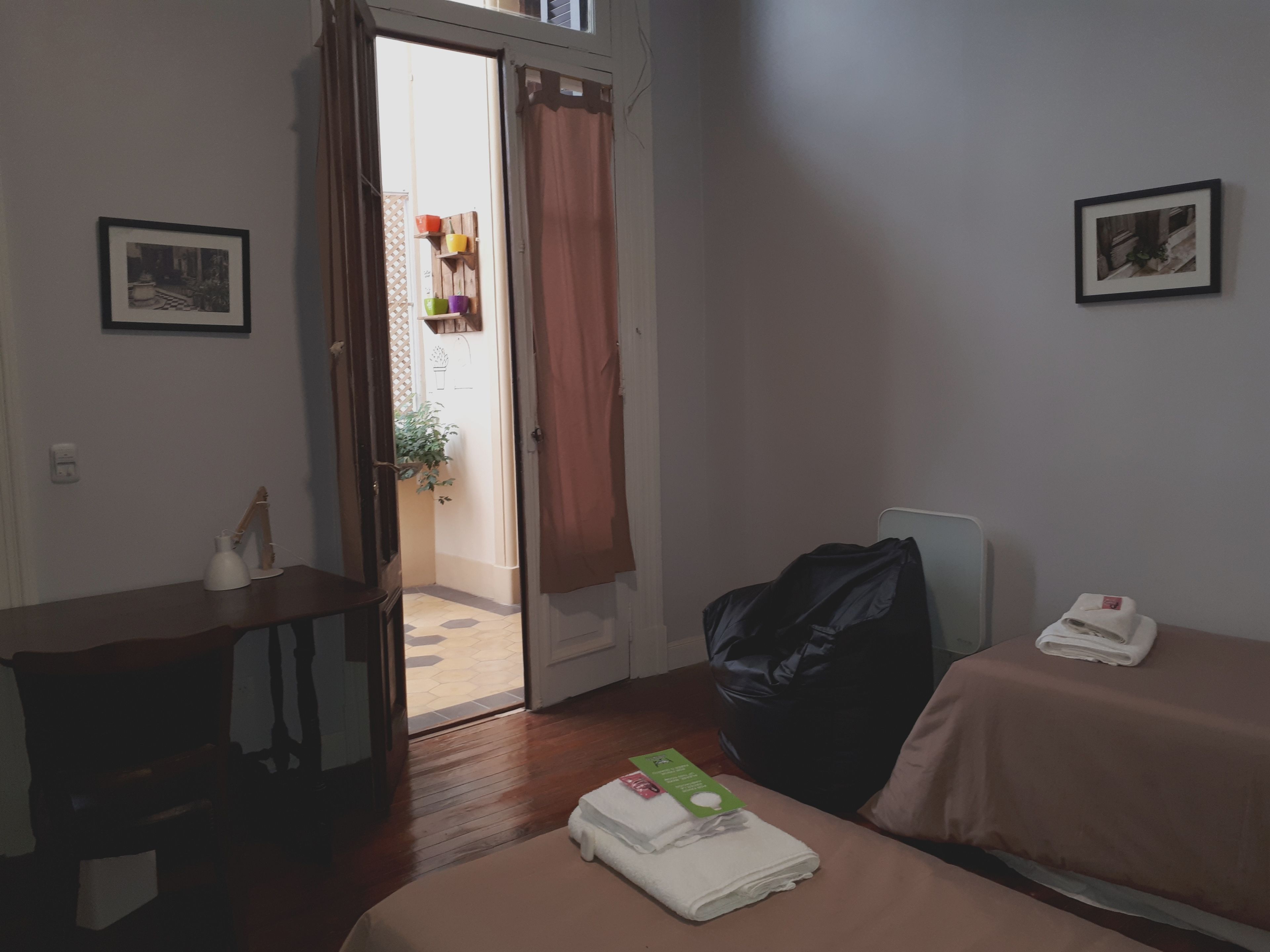 Ein Hotelzimmer mit einem Bett, einem Schreibtisch, einem Stuhl, einem Koffer und einem kleinen Tisch mit Flasche und Tasse.