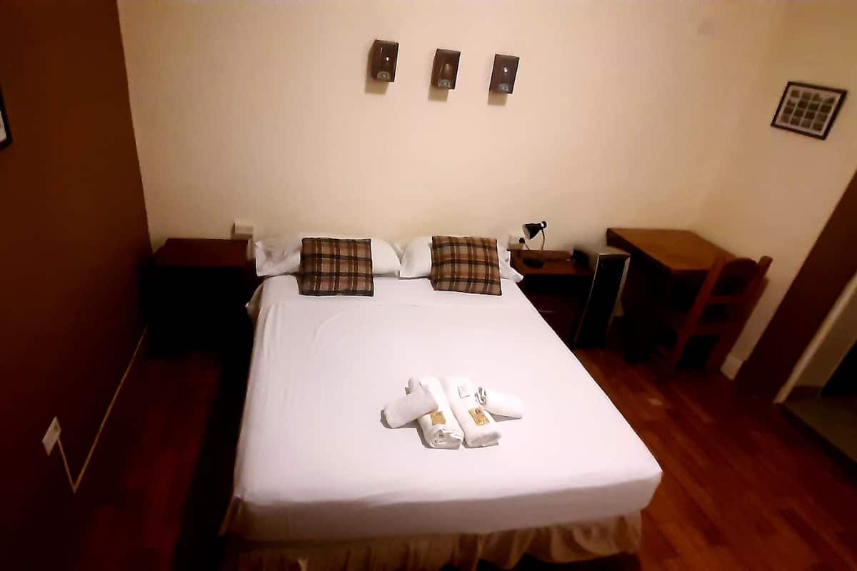 Ein Hotelzimmer mit einem Bett, Nachttischen, einem kleinen Schreibtisch und einem Stuhl.