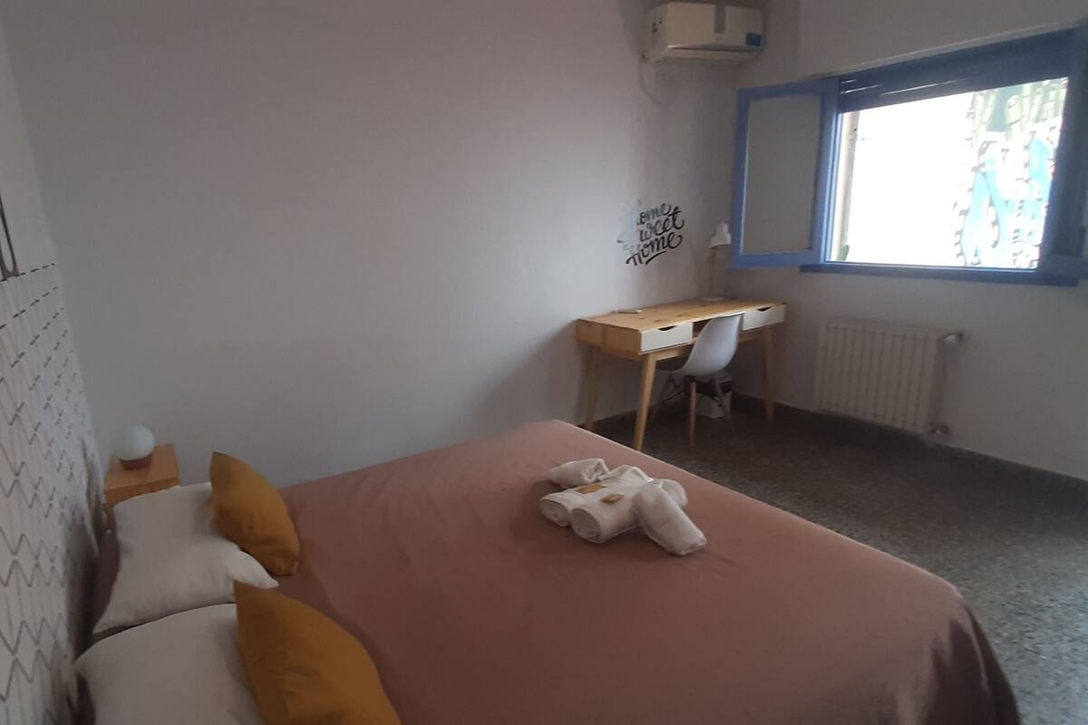 Ein Schlafzimmer mit einem Bett, einem Schreibtisch und einem Fenster.