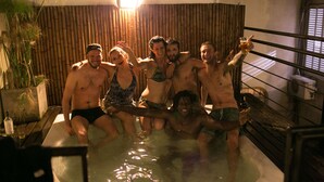 Een groep mensen in een jacuzzi met bamboe wanden en een brandende lamp.