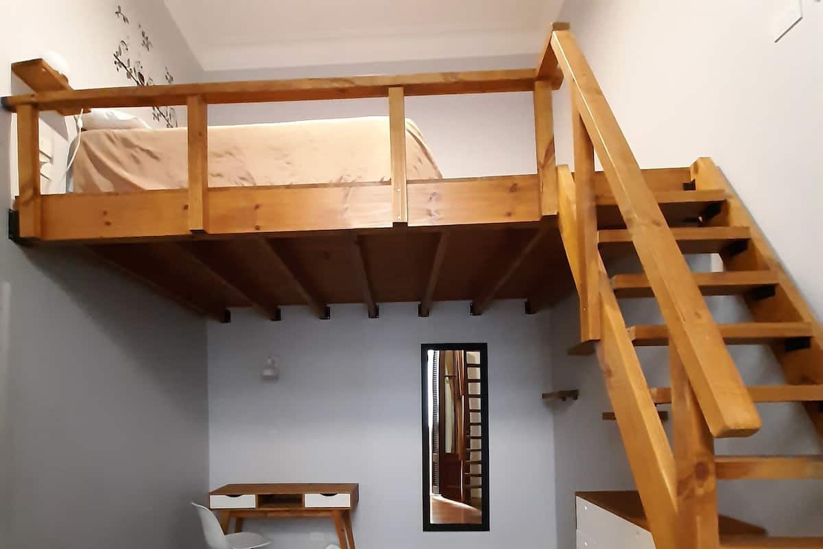 Ein Zimmer mit einem Etagenbett, einem Schreibtisch und einer Treppe.
