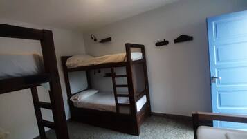Una habitación con dos literas, un estante pequeño con auriculares y una puerta azul.