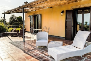 Una terrazza con mobili in vimini, un pergolato e vista sul mare.