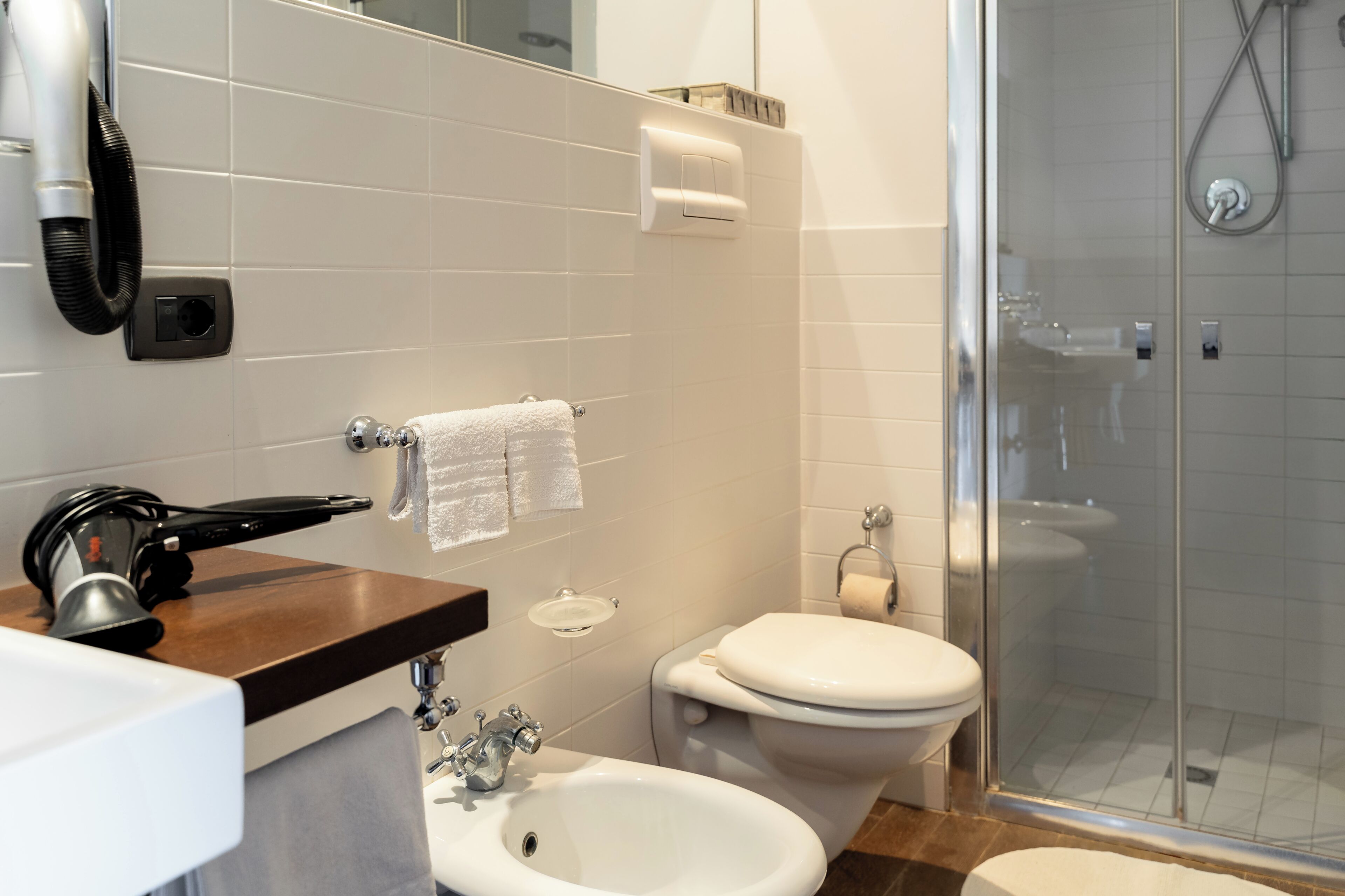 Un bagno con lavandino, bidet, WC e cabina doccia in vetro.