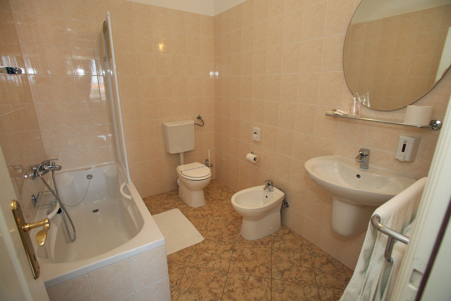 A bathroom with a bathtub, toilet, bidet, and sink.