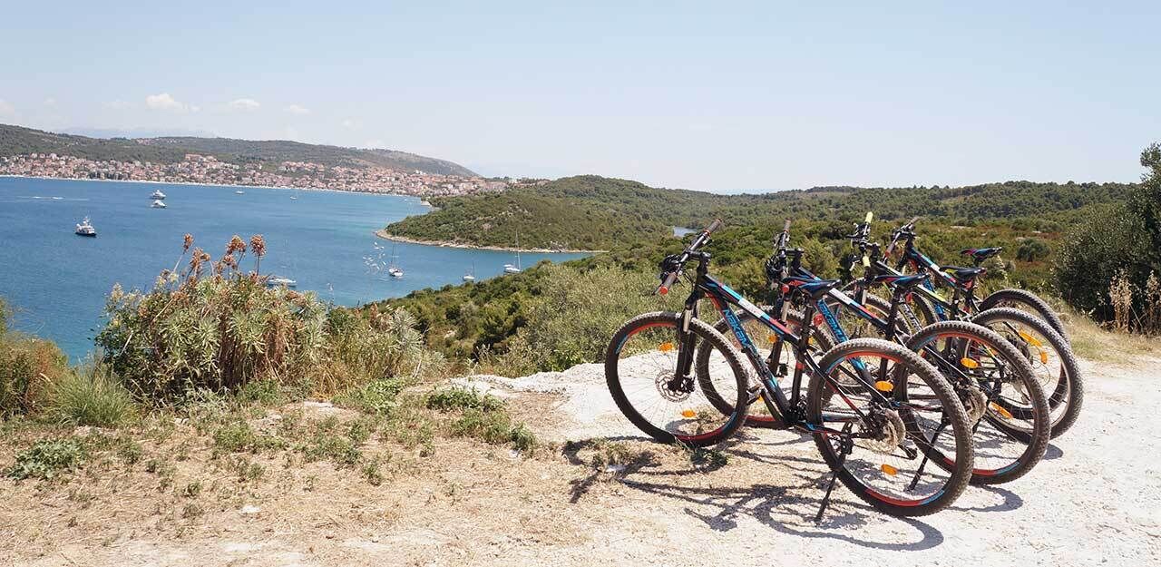 Bicycles parked on a dirt path with a coastal view.