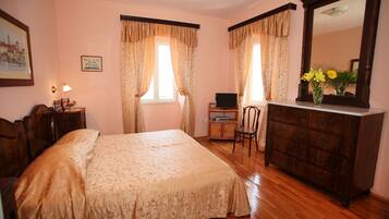 Un dormitorio con una cama, un escritorio con computadora, una silla, un aparador y un espejo.