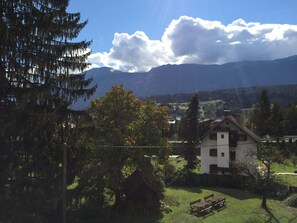 A house with a sloped roof, a small garden, and a bench. - Pension Waldkrieber (Hermagor-Pressegger See)