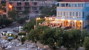 Un hôtel situé sur la côte, doté d’une terrasse donnant sur la plage, de plusieurs espaces de restauration et offrant une vue sur les bâtiments environnants qui s’étendent sur les flancs de la colline.
