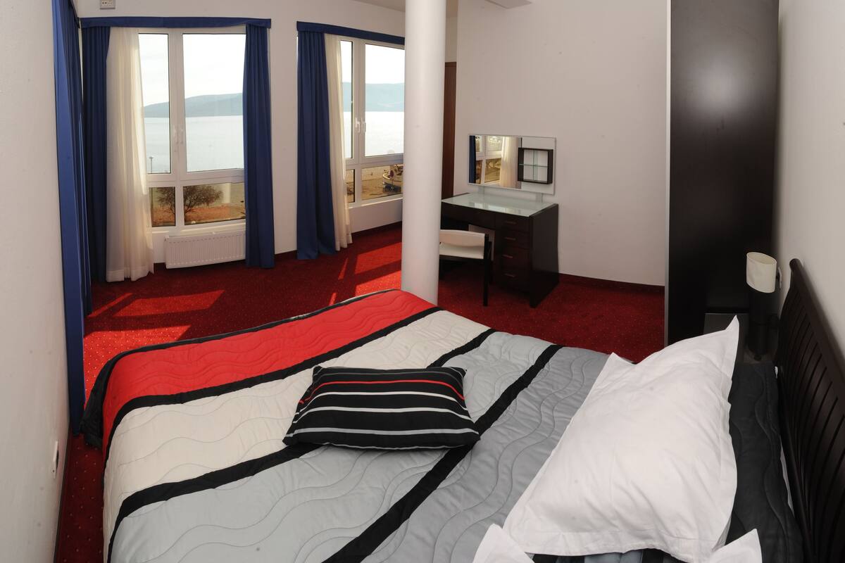 Hotellihuone, jossa on sänky, työpöytä ja näkymä merelle.