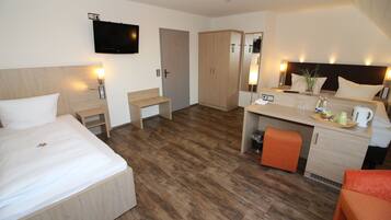 A hotel room with a bed, desk, and kitchenette.