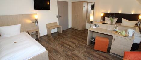 Habitación de hotel con cama, escritorio y kitchenette.
