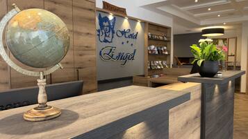 A reception desk with a globe, wooden paneling, a sign reading "Hotel & Angel", and a potted plant.